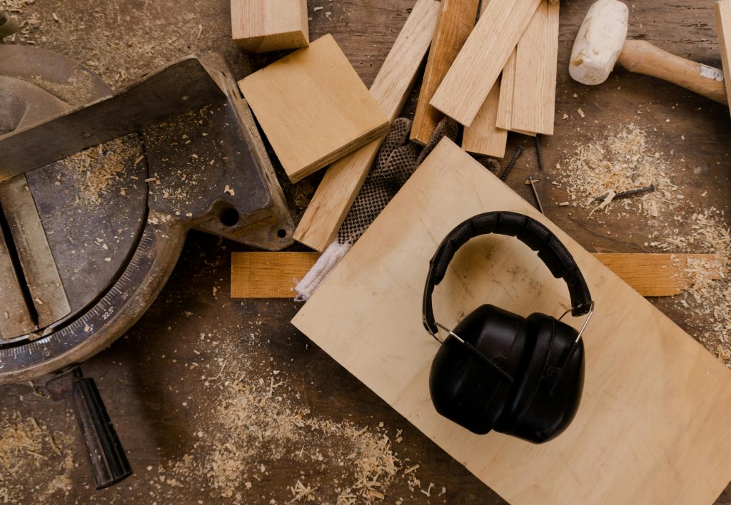Overhead view of a carpentry workspace with tools, wood planks, and ear protection.